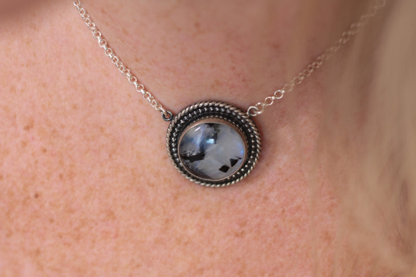 Necklace with a round moonstone pendant on a person's neck