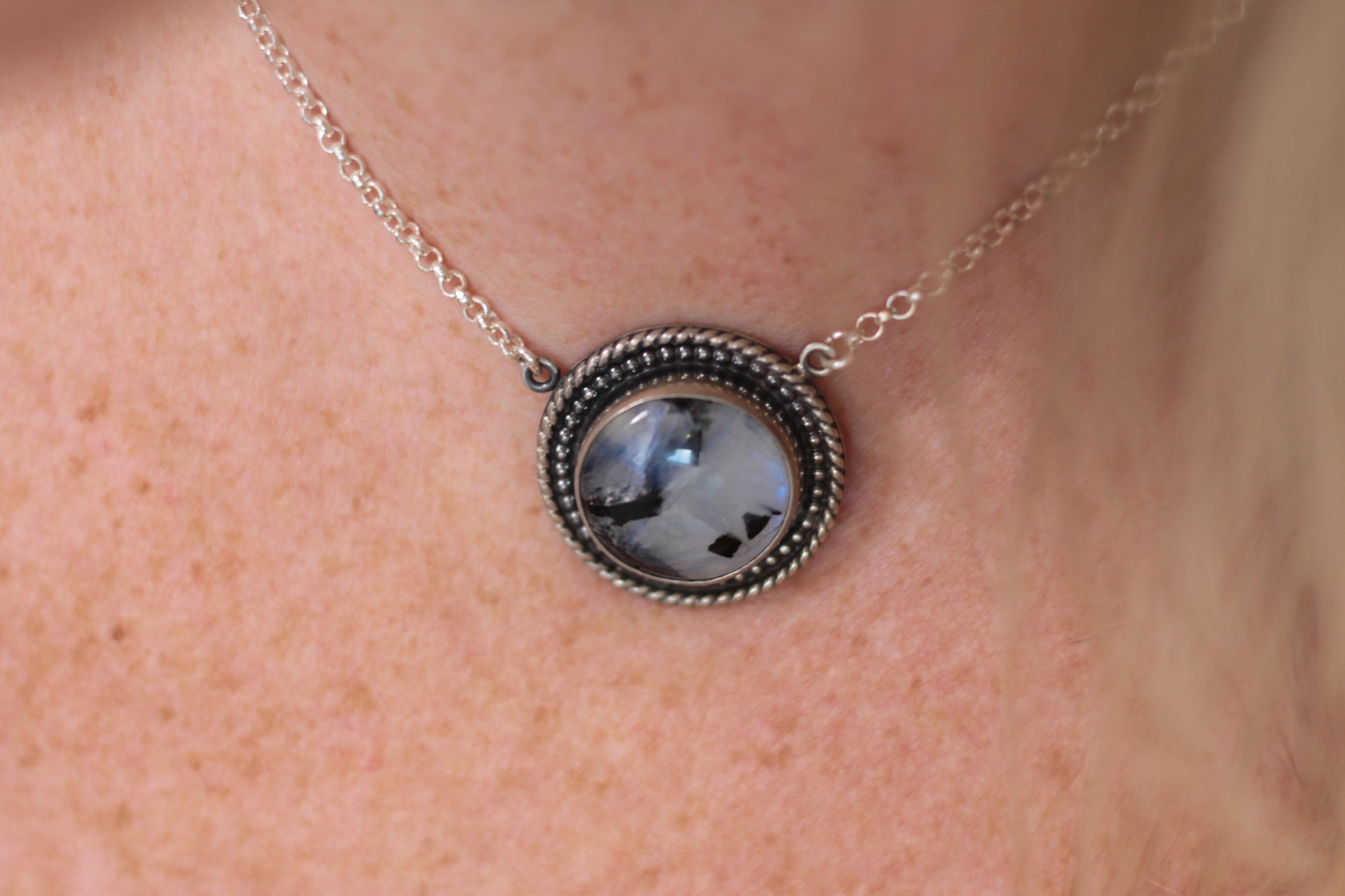 Necklace with a round moonstone pendant on a person's neck