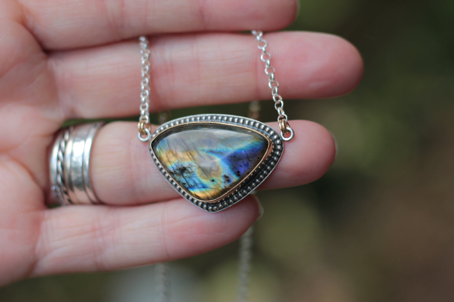Necklace with a colorful pendant held in a hand against a blurred background