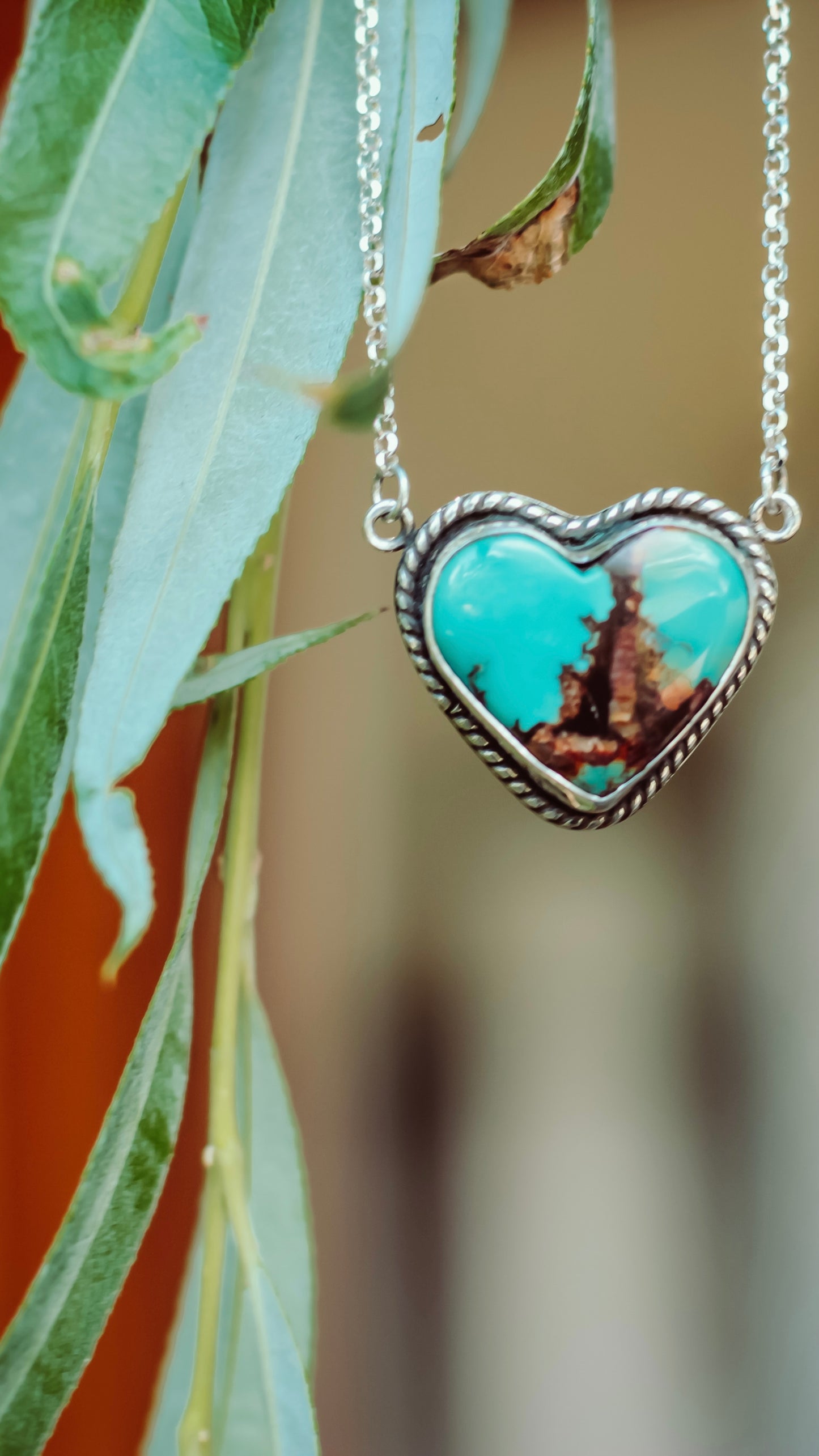 Heart-shaped turquoise pendant necklace on a blurred natural background