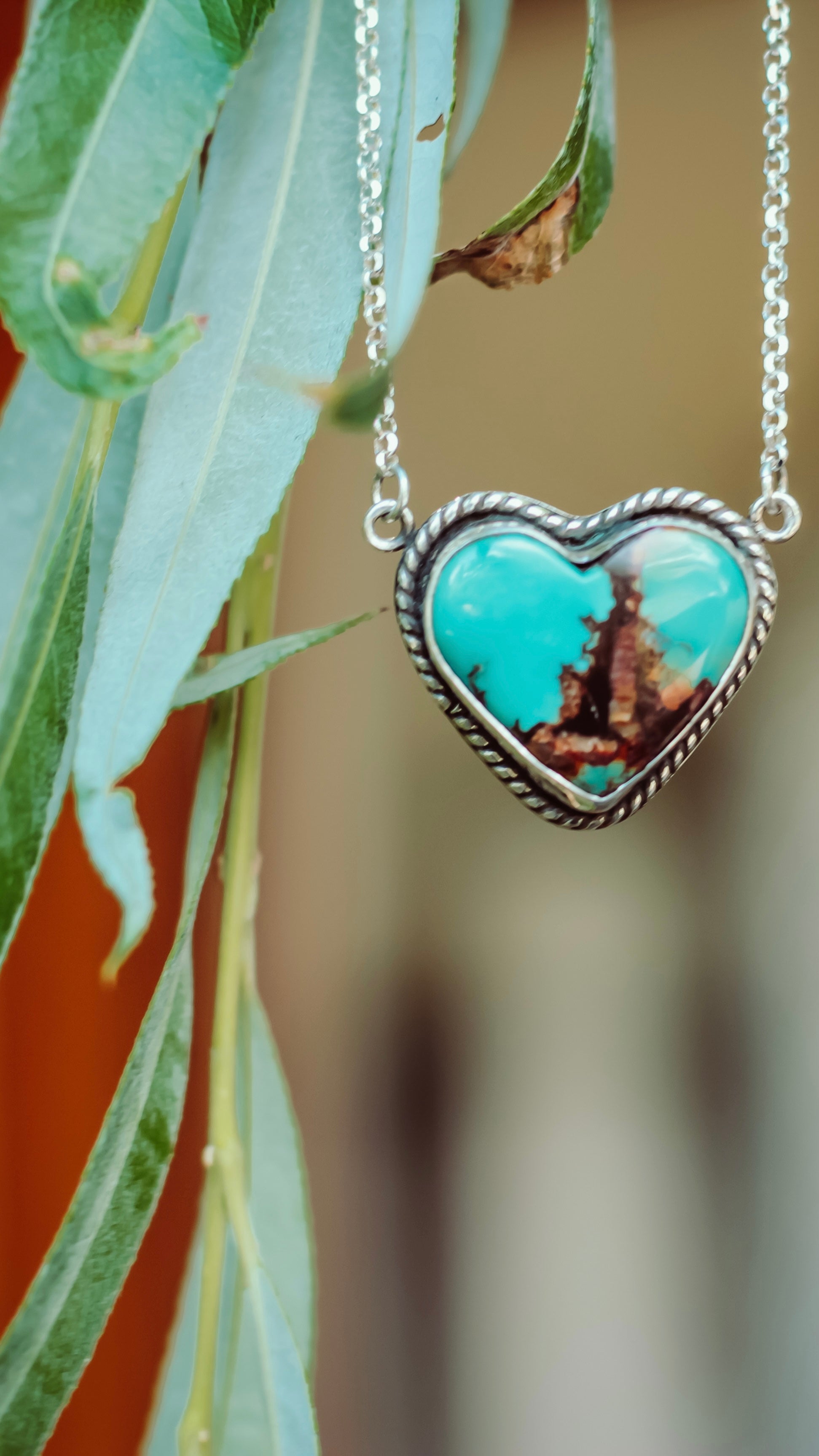Heart-shaped turquoise pendant necklace on a blurred natural background