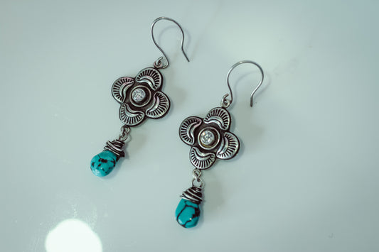 Pair of silver earrings with turquoise beads on a white background