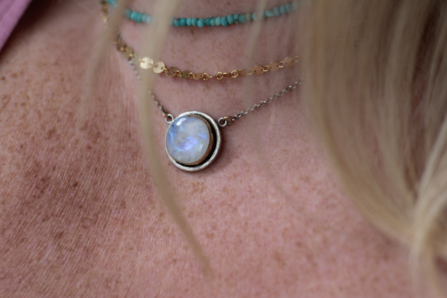 Necklace with a round pendant on a person's neck